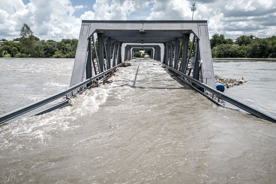 A partially submerged bridge sits in the middle of a body of water.