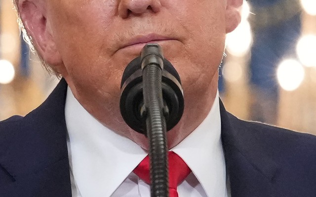 A close-up of Trump's face in front of a microphone, from the nose down