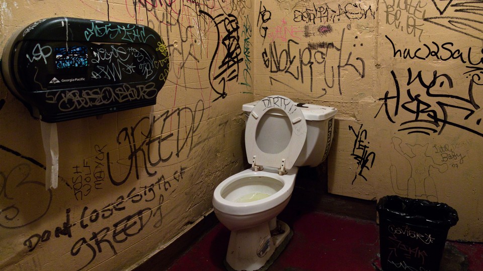 A dirty bathroom with graffiti on the walls