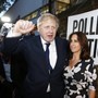Boris Johnson raises his hand in a fist while standing with his wife outside a polling station on the day of the Brexit vote.
