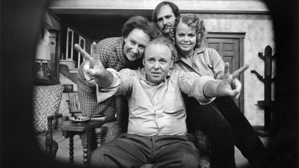 A black-and-white photo shows the cast of "All in the Family," playing a set of parents, a daughter, and a son-in-law.