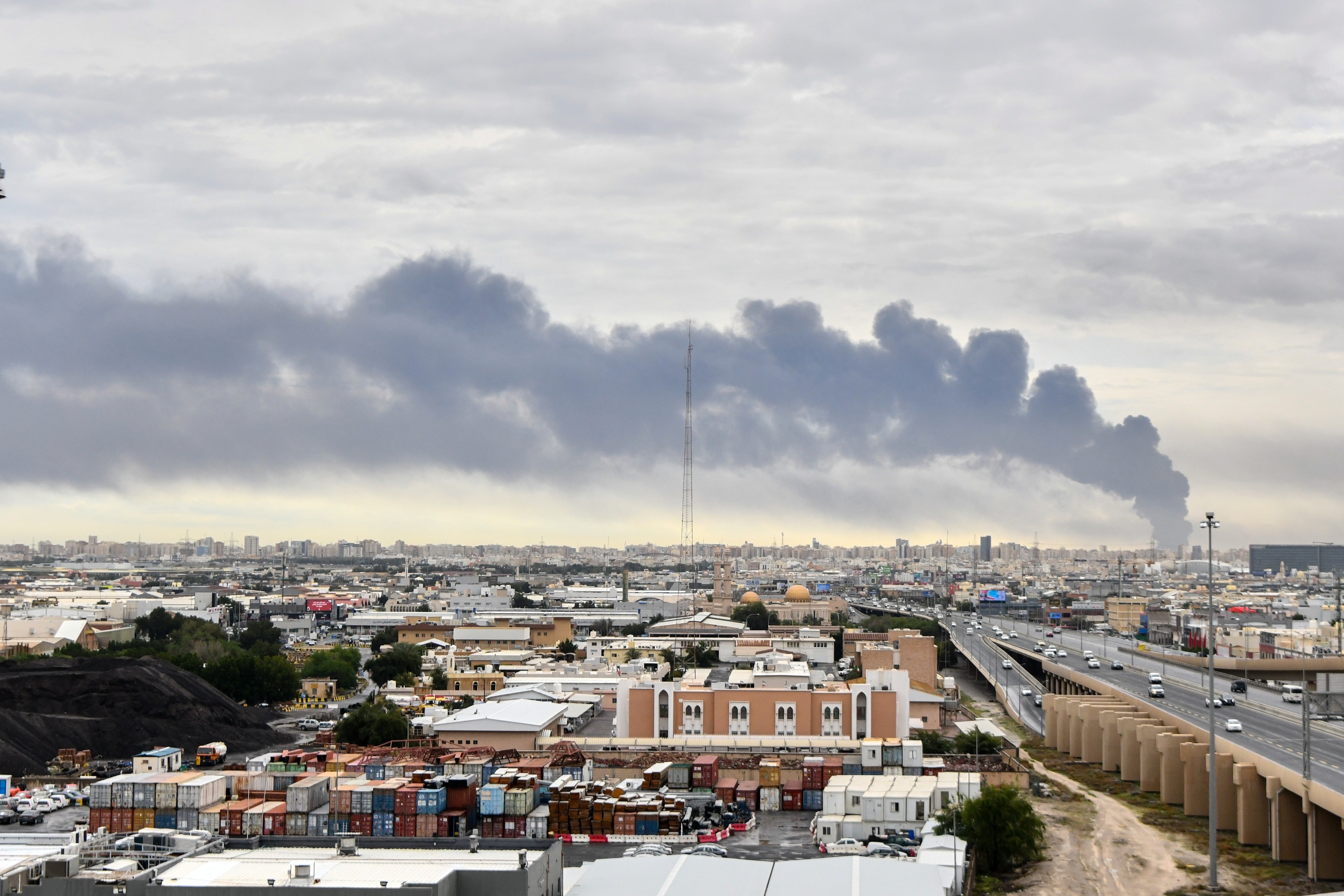 Dark smoke rises above buildings, seen from a distance.