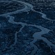 Ice masses break up a body of water in a dark landscape.