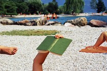 A photo of a person reading outdoors on a beach.