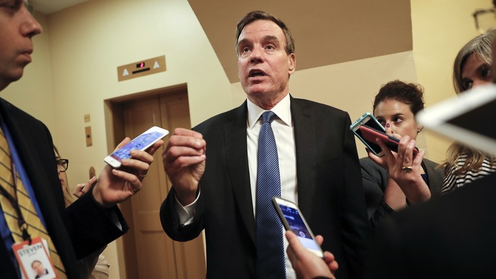 Virginia Senator Mark Warner speaks with reporters carrying cell phones.