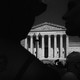 A black-and-white photo of a protester silhouetted in front of the U.S. Supreme Court