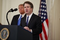 Brett Kavanaugh speaks at a podium with President Trump and an American flag in the background