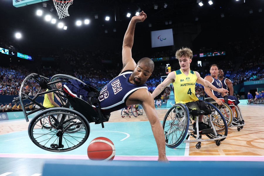 A wheelchair basketball player falls during a game.