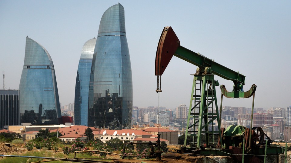 an oil pump works a nearby hill in Baku, Azerbaijan