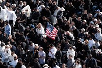 In a crowd of Catholics, one holds up an American flag