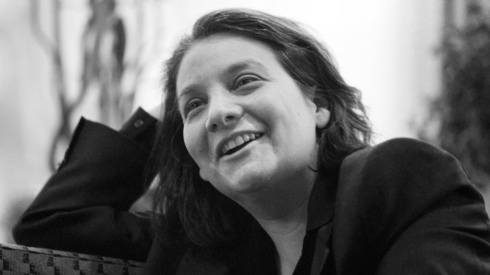 Black-and-white photo of a woman with dark hair, smiling with her head tilted, in a black jacket.