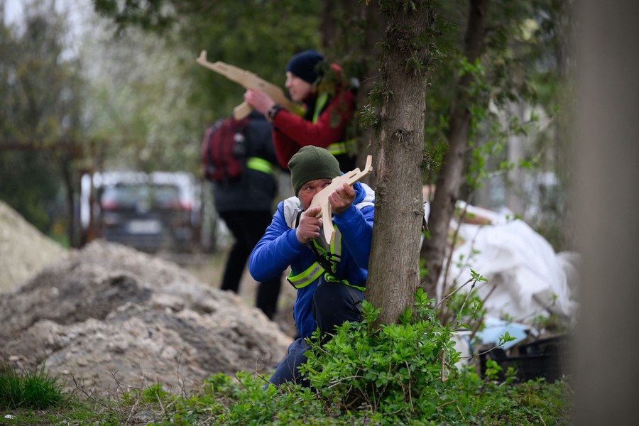 Several people train to handle weapons, using wooden replica rifles.