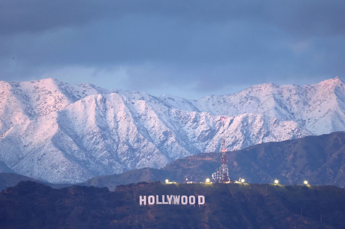 A distant view of the famous "Hollywood" sign, with snow-covered mountains in the background