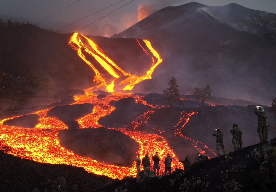 Lava flows in several streams, observed by about a dozen people on a hillside.