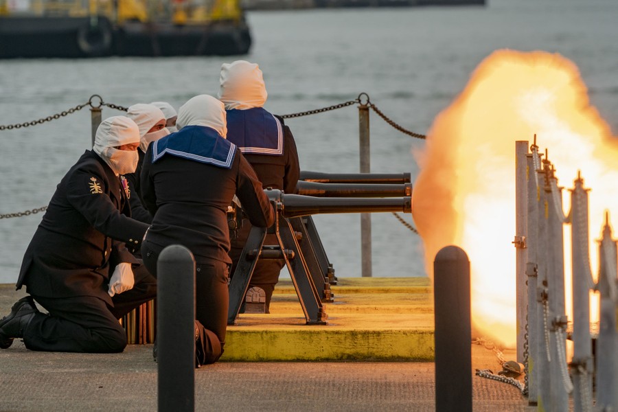 Sailors fire several small cannons.