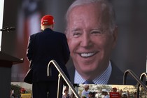 Trump stands in front of a photo of Biden