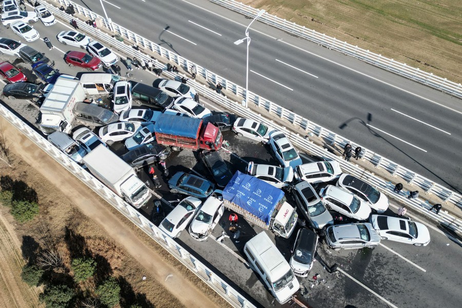 An aerial view of dozens of cars smashed together on a stretch of highway.