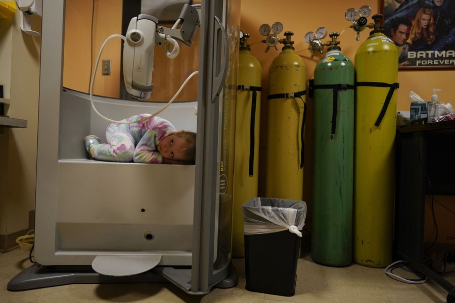 A child lies curled up inside a small test chamber in a hospital.