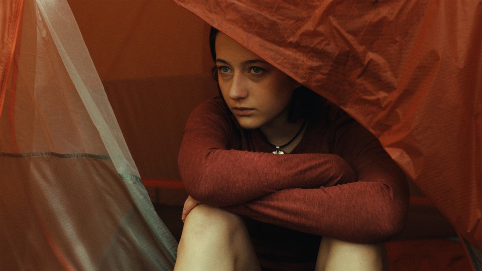 girl sitting at the opening of a tent peering out