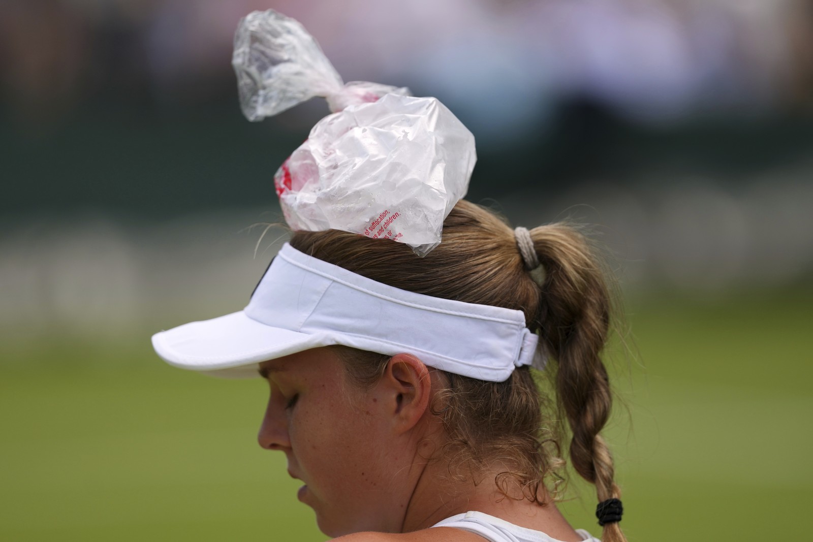 A tennis player has an ice bag on their head, using it to cool off.