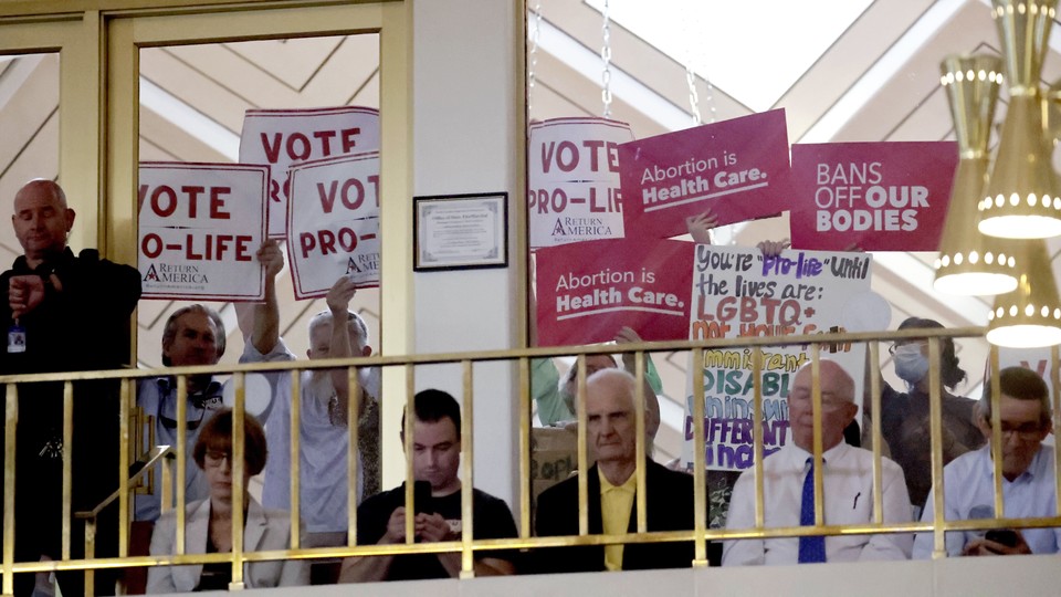 A photo of anti-abortion protesters holding up signs to the windows of a legislative assembly