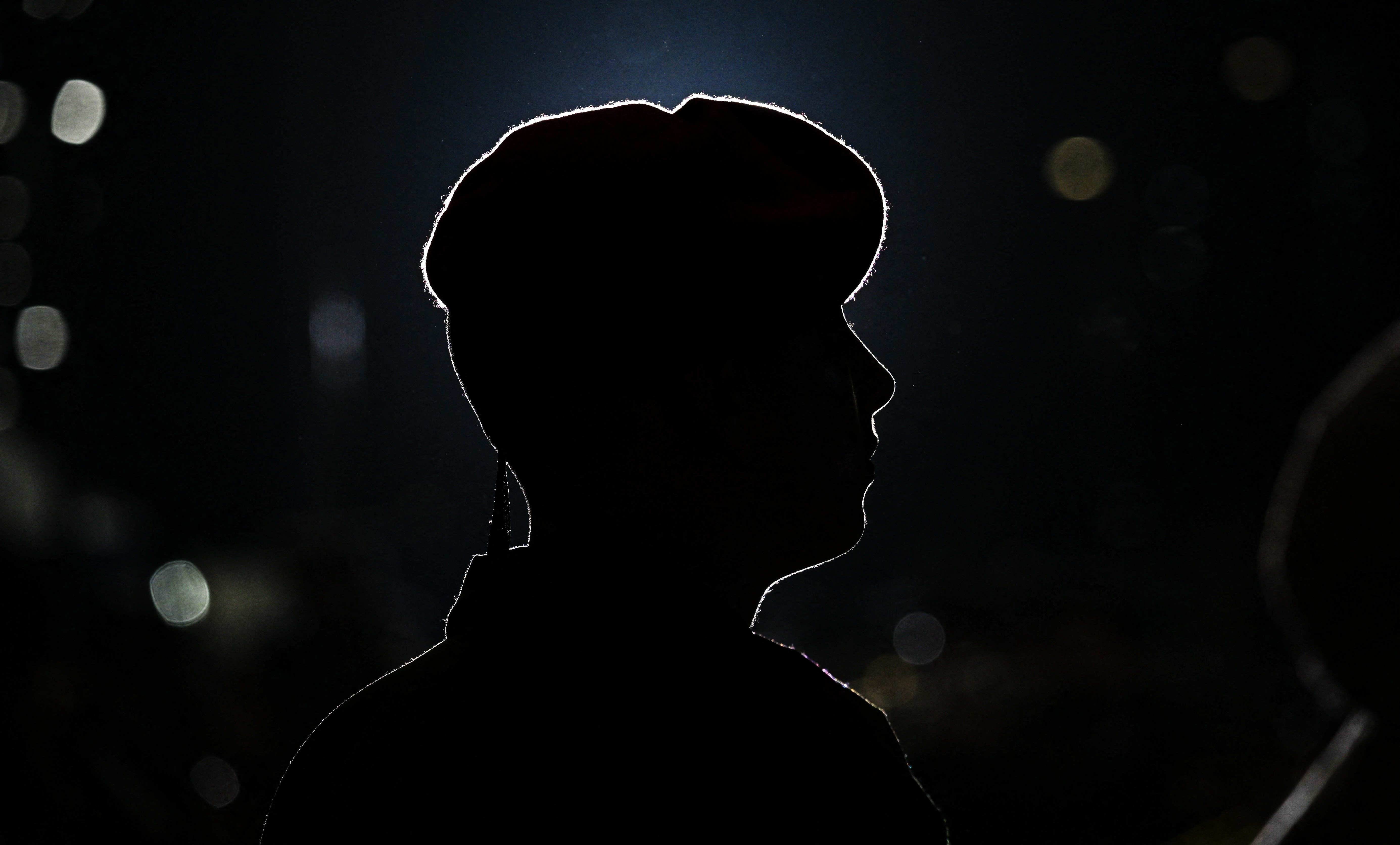 A soldier wearing a beret, seen in silhouette