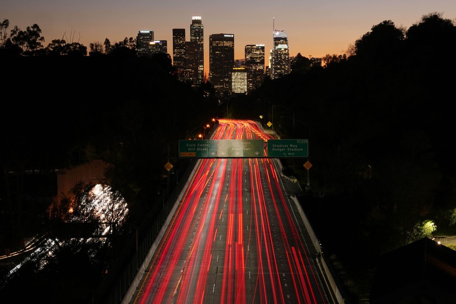 Cars' lights create red streaks on a highway leading to the Los Angeles skyline.