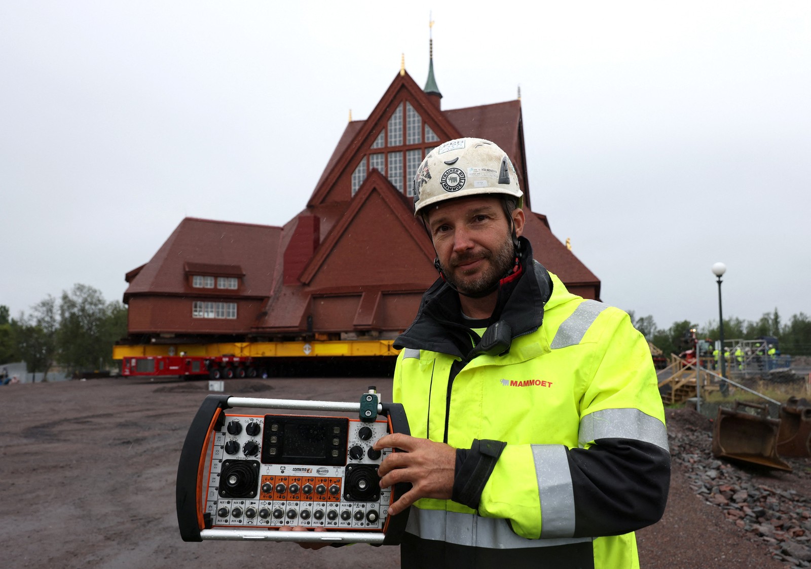 A worker in a hi-vis jacket holds up a complex remote control.