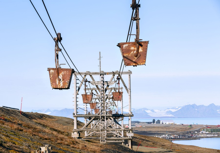 Huge rusty buckets hang from an abandoned cableway.