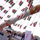 A boy holding a placard with pictures of President Hassan Rouhani, Ayatollah Ruhollah Khomeini, and Ayatollah Ali Khamenei, poses for camera in front of a model of Simorgh satellite-carrier rocket with Iranian flags everywhere. 
