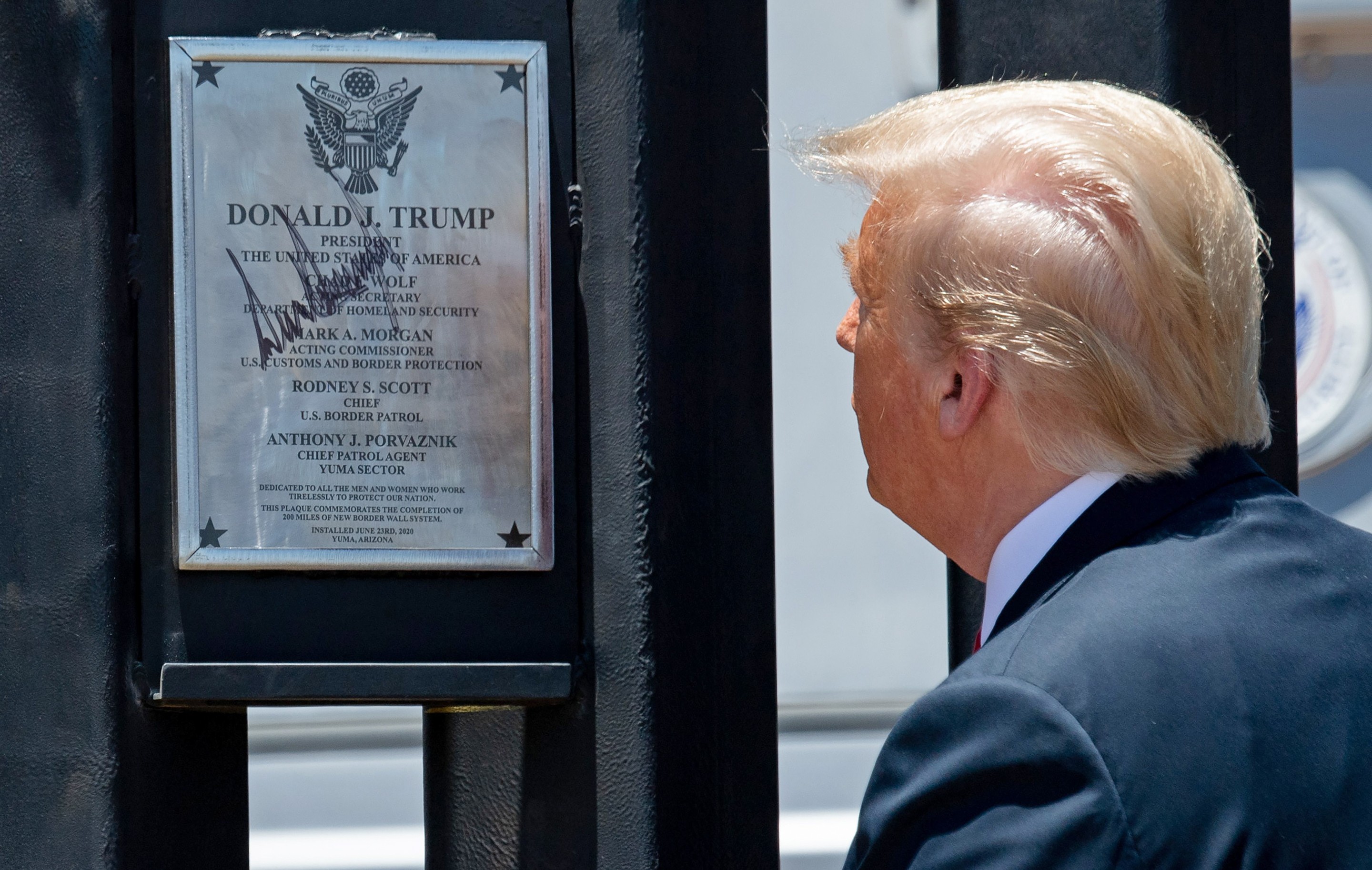 Donald Trump looks at a plaque that he signed