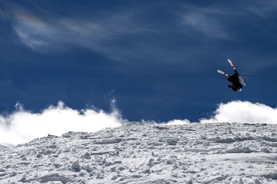 A skier jumps on a snowy hillside.