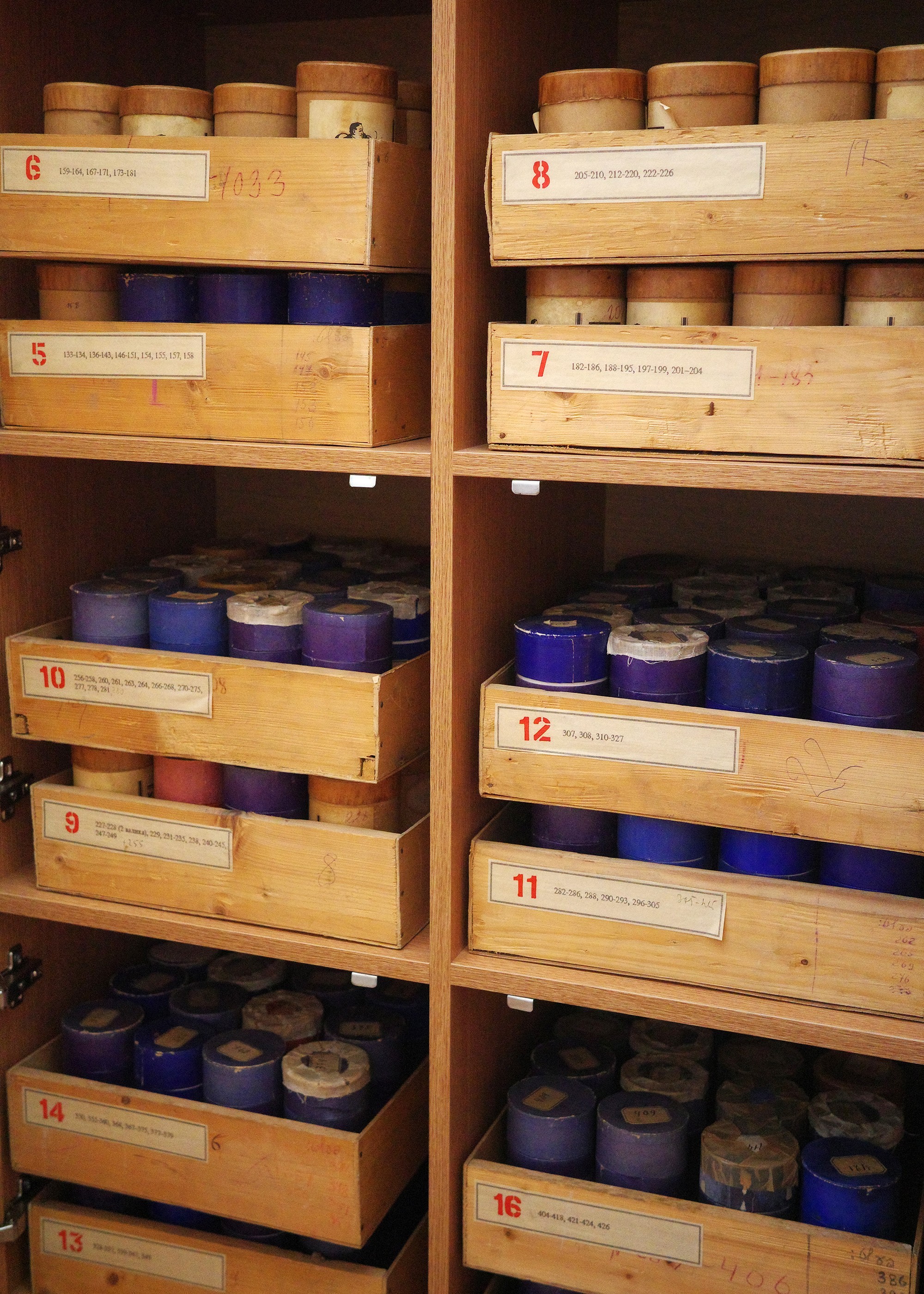 photo of wooden shelves stacked with numbered wooden crates, each holding dozens of cylindrical containers