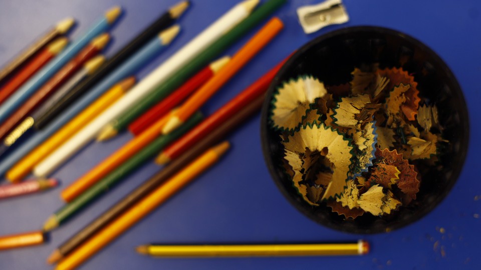 Colored pencils alongside a sharpener and a bowl of shavings