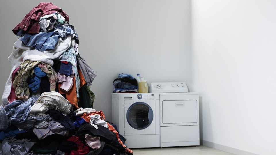 A towering pile of laundry next to a washing machine