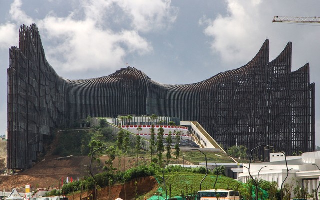 A tall and wide steel structure, under construction, with rounded winglike features