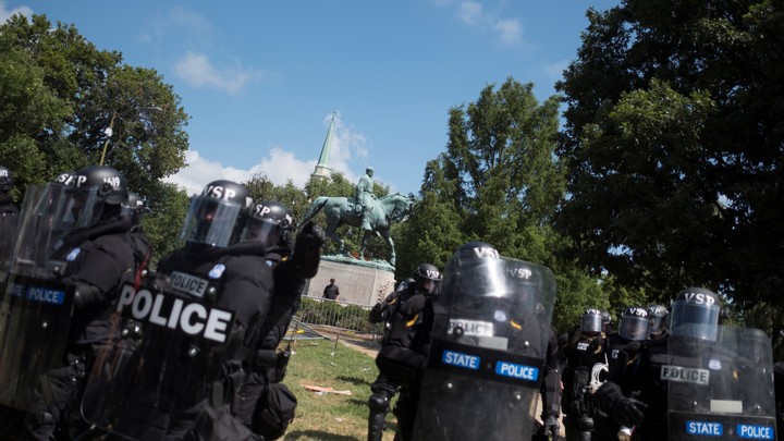 Riot police stand in formation in Charlottesville with a statue of Robert E. Lee behind them.