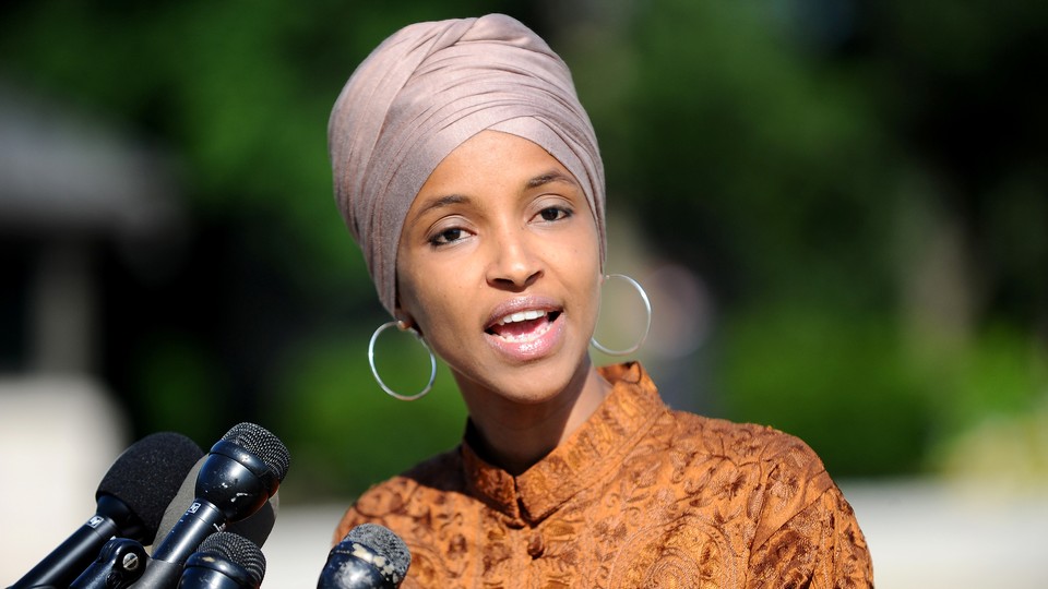 Ilhan Omar stands in front of microphones.