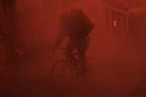 A person riding a bicycle in a red fog 