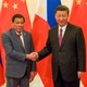 President Xi Jinping shakes hands with Philippines President Rodrigo Duterte in front of Chinese and Filipino flags.