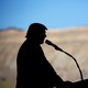 Donald Trump stands silhouetted against mountains in the background.