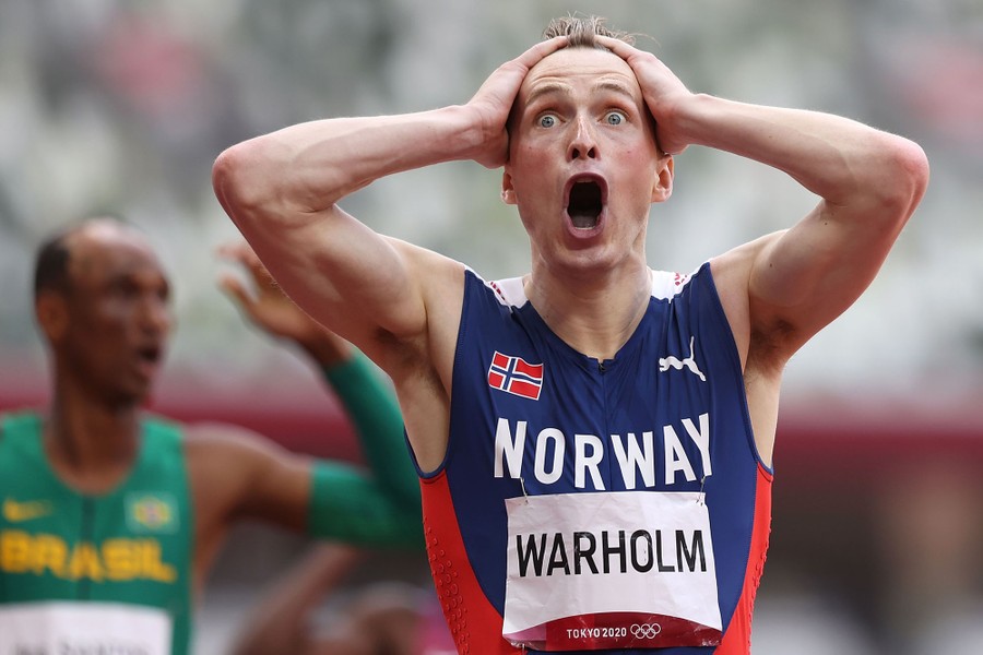 An athlete reacts after winning a race, hands on head, and eyes and mouth wide open.