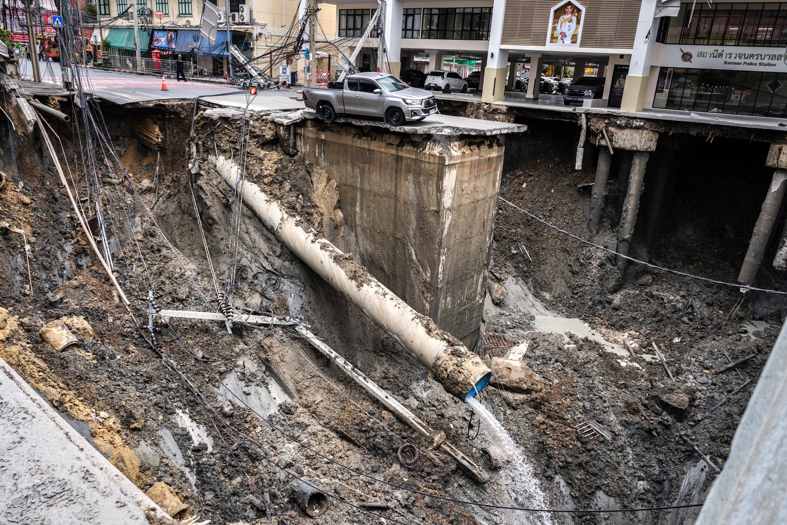 A vehicle sits on the edge of a huge hole in the ground after a road collapsed.