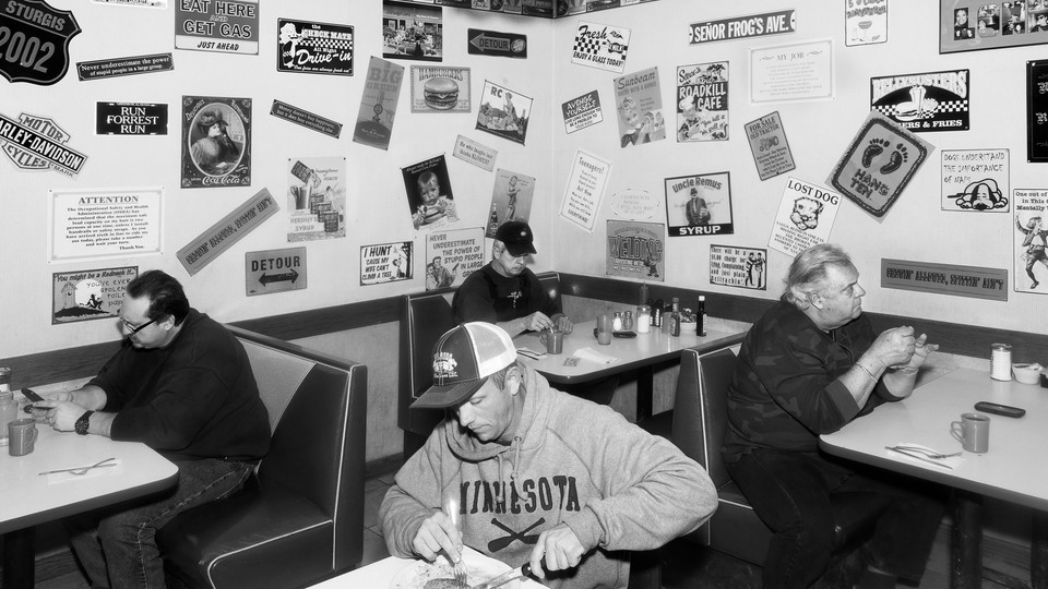 A black-and-white photo of people eating by themselves in a restaurant