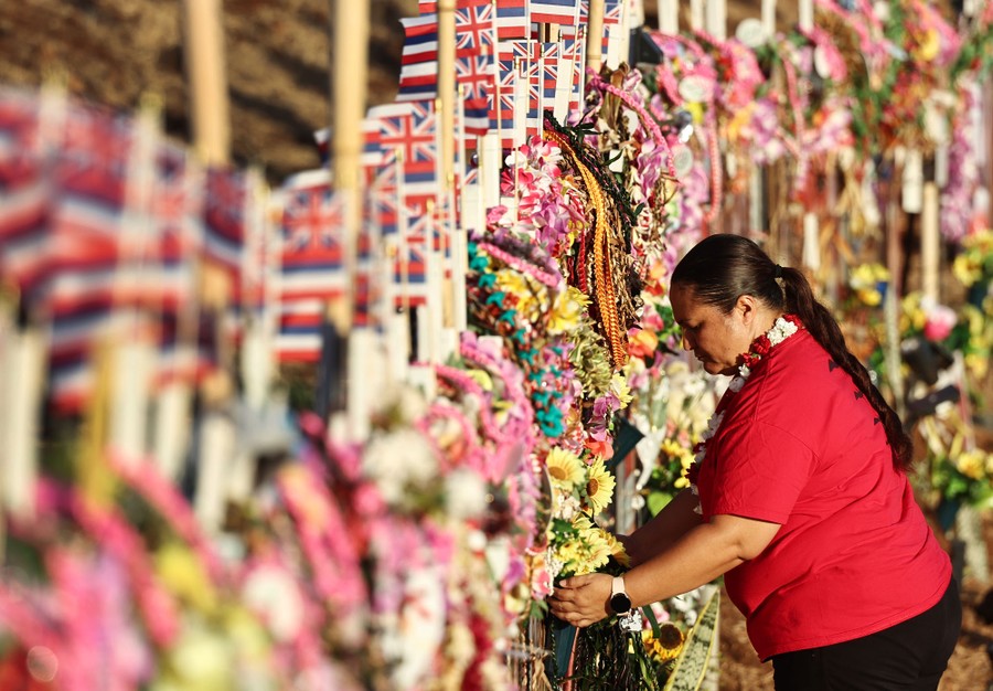 A person adjusts flowers at a memorial.