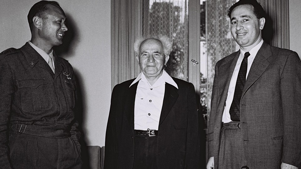 David Ben-Gurion, center, then Israel's defense minister, stands with Moshe Dayan, the military's Chief of Staff, left, Shimon Peres, the director general of the Ministry of Defense in Tel Aviv on February 2, 1955. 