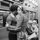 Black-and-white photograph of a couple holding each other on a crowded subway car