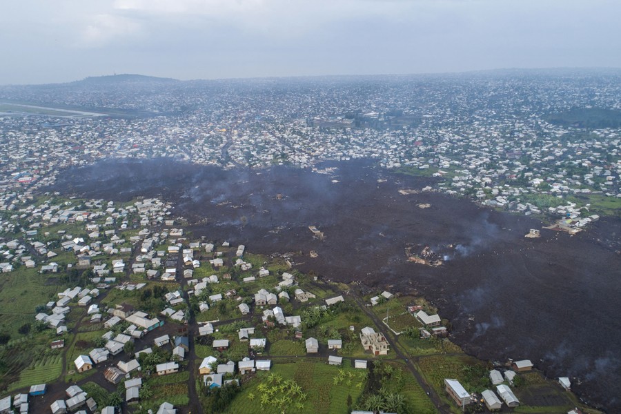 A wide strip of dark volcanic rock protrudes into a neighborhood, seen from above.