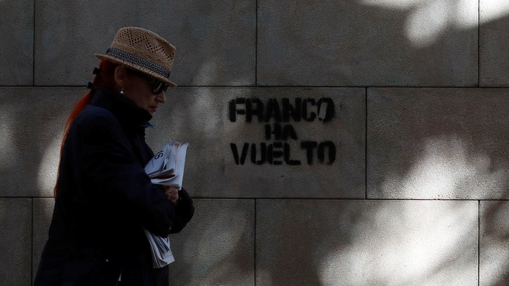 A woman walks past a graffiti which reads "Franco is back" in Barcelona, Spain on October 22, 2017.