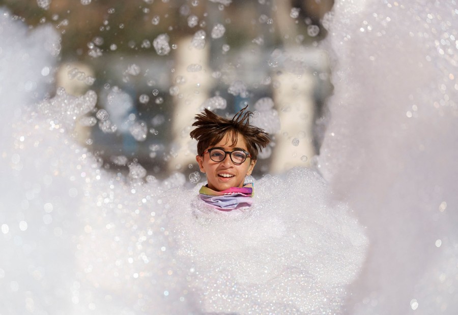A young person runs through piles of foam, with only their head visible.